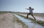 <span class="caption-caption">Jumping the many-kilometres-long bore drain near Cunnamulla</span>, c1960s. <br />Slide, collection of <span class="caption-contributor">John Thun</span>.