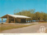 <span class="caption-caption">Log cabin shelter, Woodgate Beach</span>, c1964. <br />Postcard folder by <span class="caption-publisher">Murray Views Pty Ltd</span>, collection of <span class="caption-contributor">Centre for the Government of Queensland</span>.